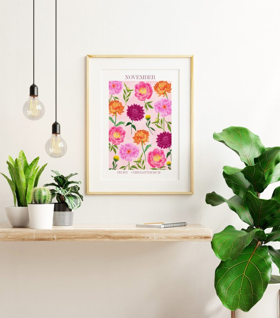 A framed art print of pink peony and orange chrysanthemum birth flowers in a bright modern living space, a cheerful November birthday gift idea.