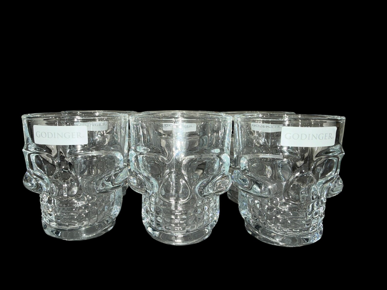 A set of five clear glass skull shaped shot glasses by Godinger, fun and spooky Halloween glasses for a party bar setup.