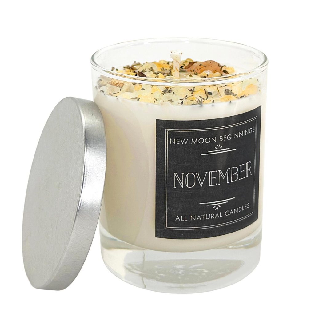 A white soy candle in a glass jar topped with citrine chips and dried botanicals with a silver lid, an elegant and natural November birthday gift idea.