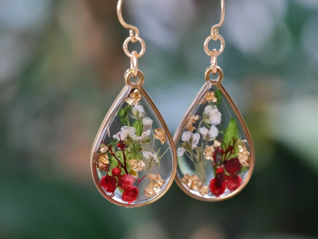Gold teardrop resin earrings with pressed holly and white flowers inside, charming birth flower jewelry among December birthday gift ideas.
