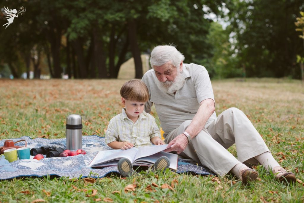 grandpa and grandson reading a book together a picnic in the park