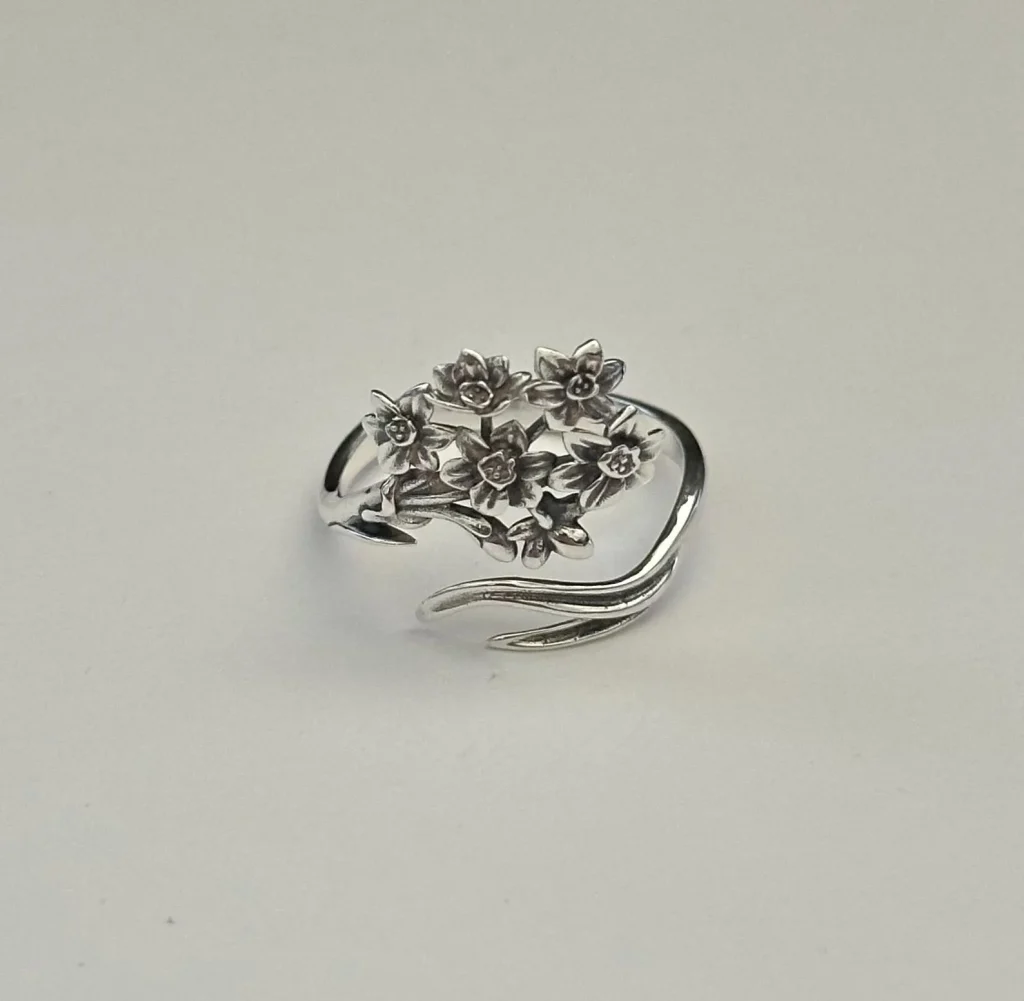 A sterling silver adjustable narcissus flower ring with detailed petals, a delicate and unique December birthday gift idea.