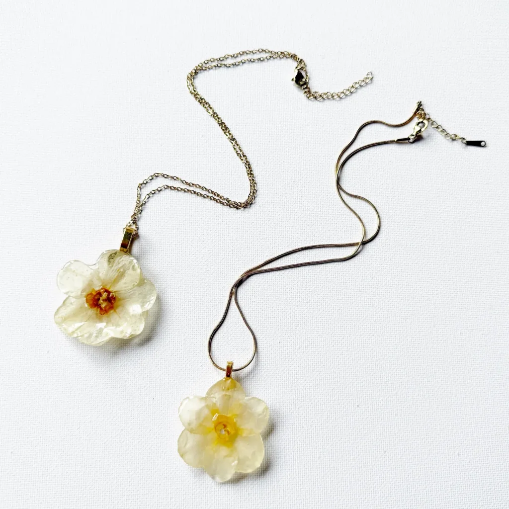 Two real narcissus flower pendant necklaces in resin on gold and silver chains, lovely December birthday gift ideas.