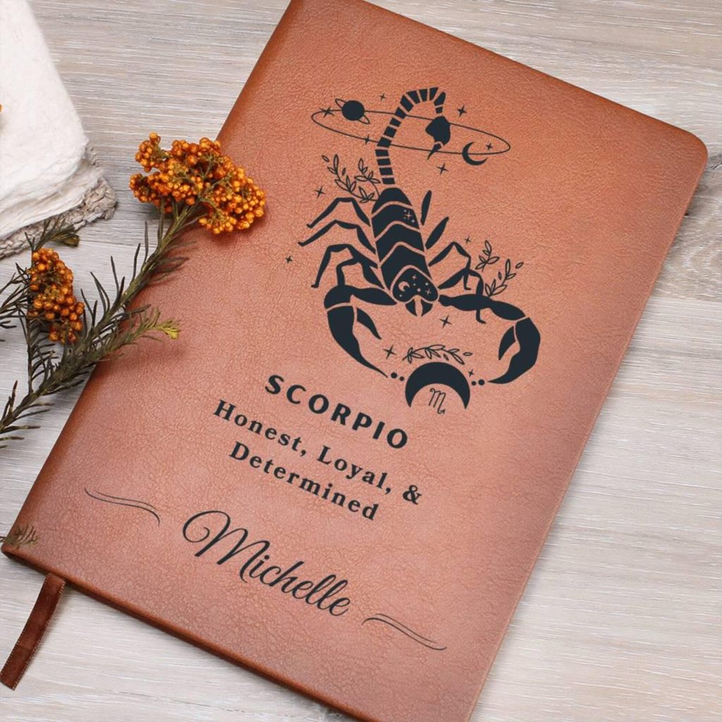 A tan leather journal embossed with a celestial scorpion illustration and personalized name, making it one of the most meaningful October birthday gift ideas.