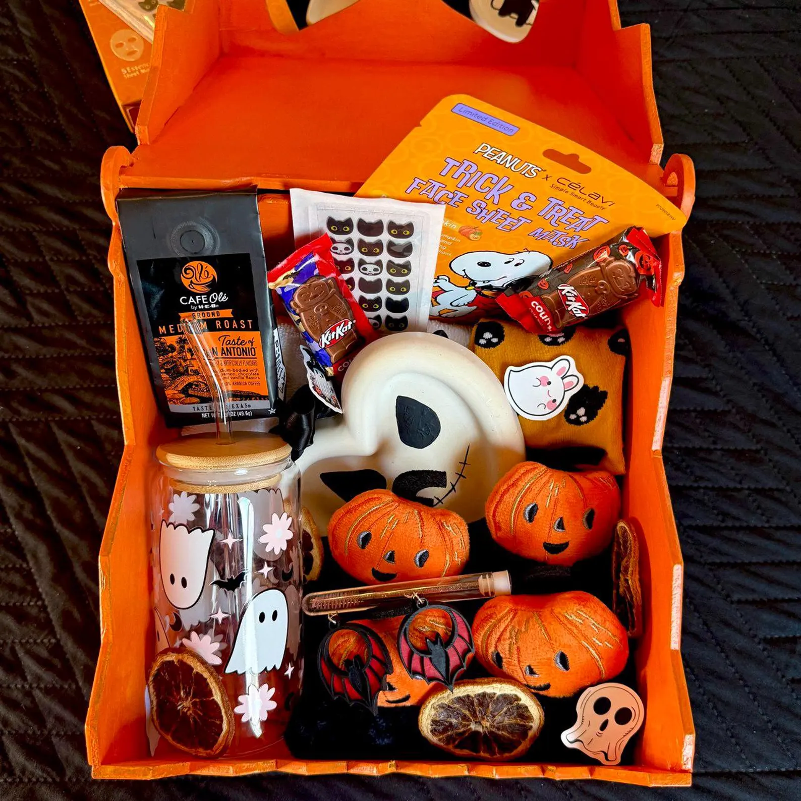 An orange Halloween boo basket for families packed with coffee, candy, a ghost tumbler, face mask and pumpkin plushies.