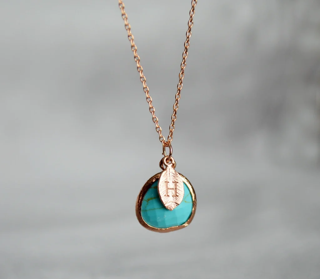 A rose gold turquoise pendant necklace with a personalized initial leaf charm, a meaningful December birthday gift idea.