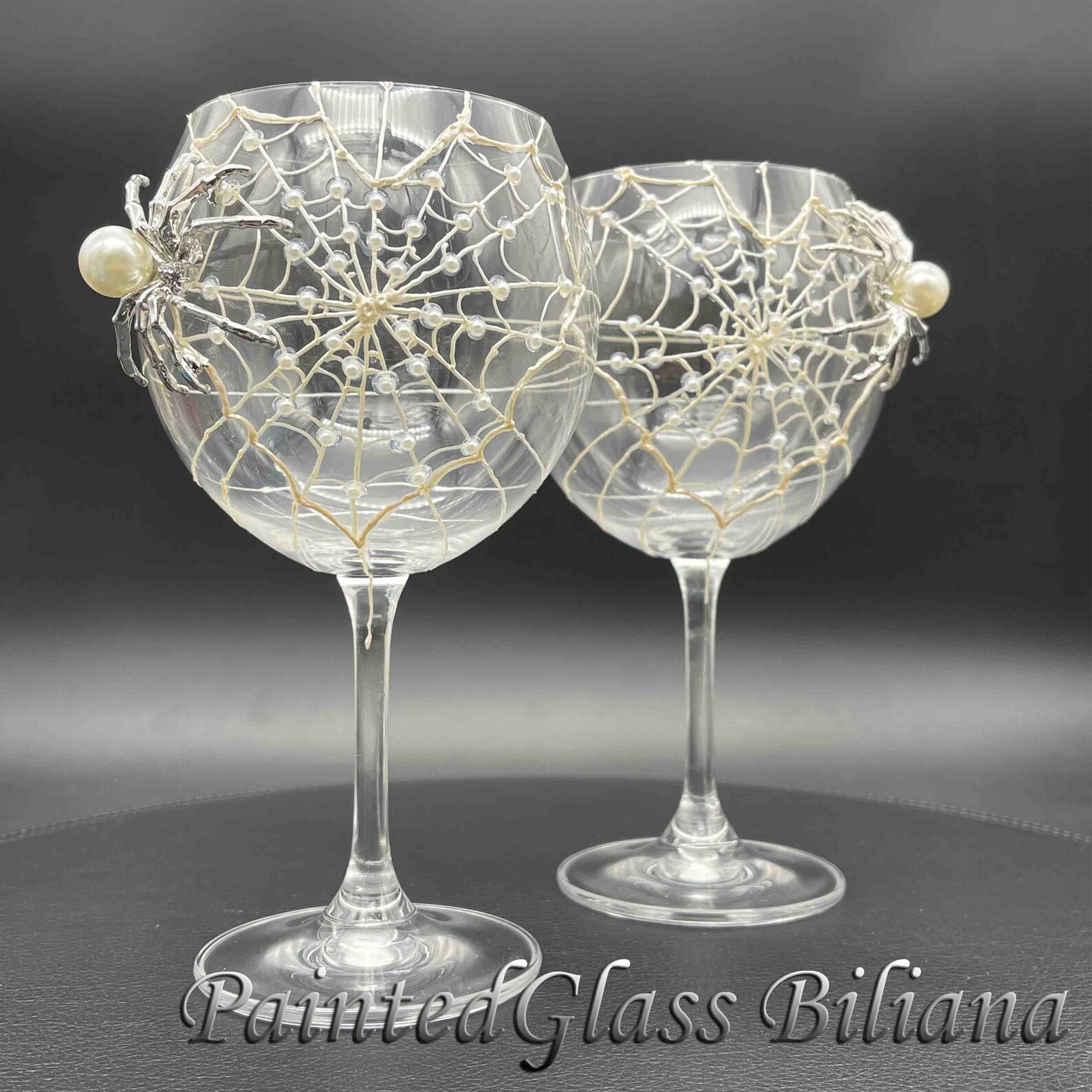 Two elegant stemmed Halloween glasses decorated with pearl spiderweb designs and silver spider charms, perfect spooky Halloween glasses.