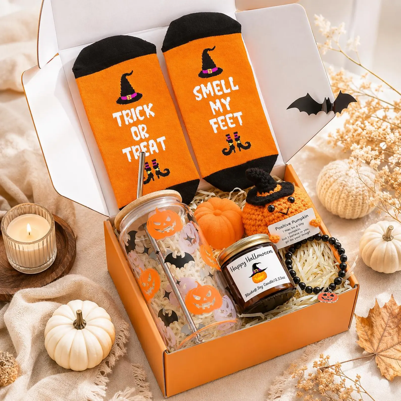 An orange Halloween boo basket for teens filled with novelty socks, a glass tumbler, candle, bracelet and crochet pumpkin.