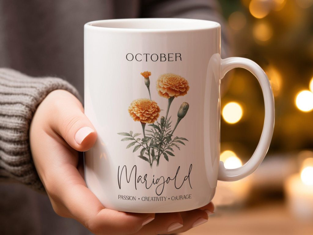A woman holding a white ceramic mug featuring an orange marigold botanical illustration, a charming and affordable October birthday gift idea.