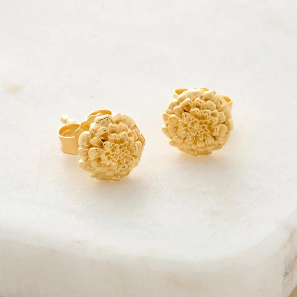 Gold marigold flower stud earrings with detailed petal texture displayed on a marble surface, charming October birthday gift ideas for her.