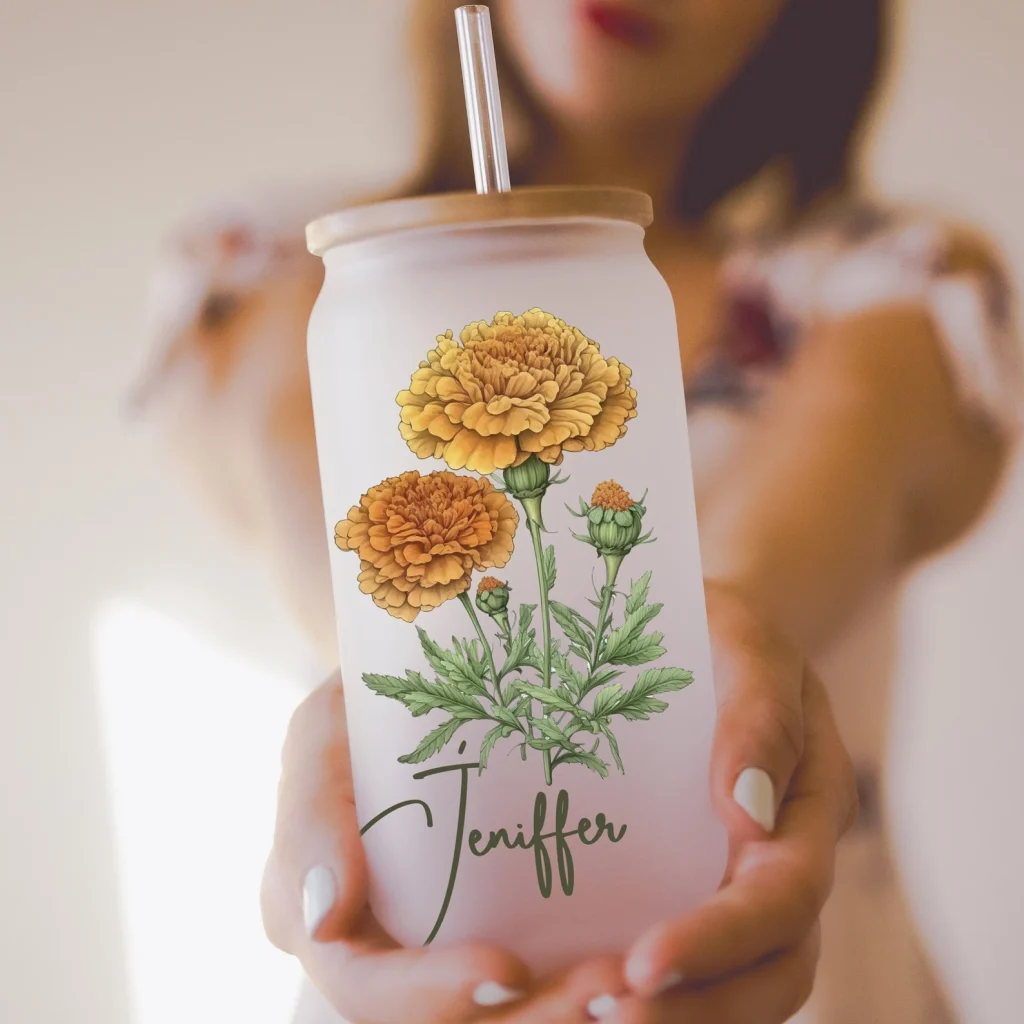 A woman holding a personalized frosted glass tumbler with a bamboo lid featuring an orange marigold illustration, a gorgeous October birthday gift idea.