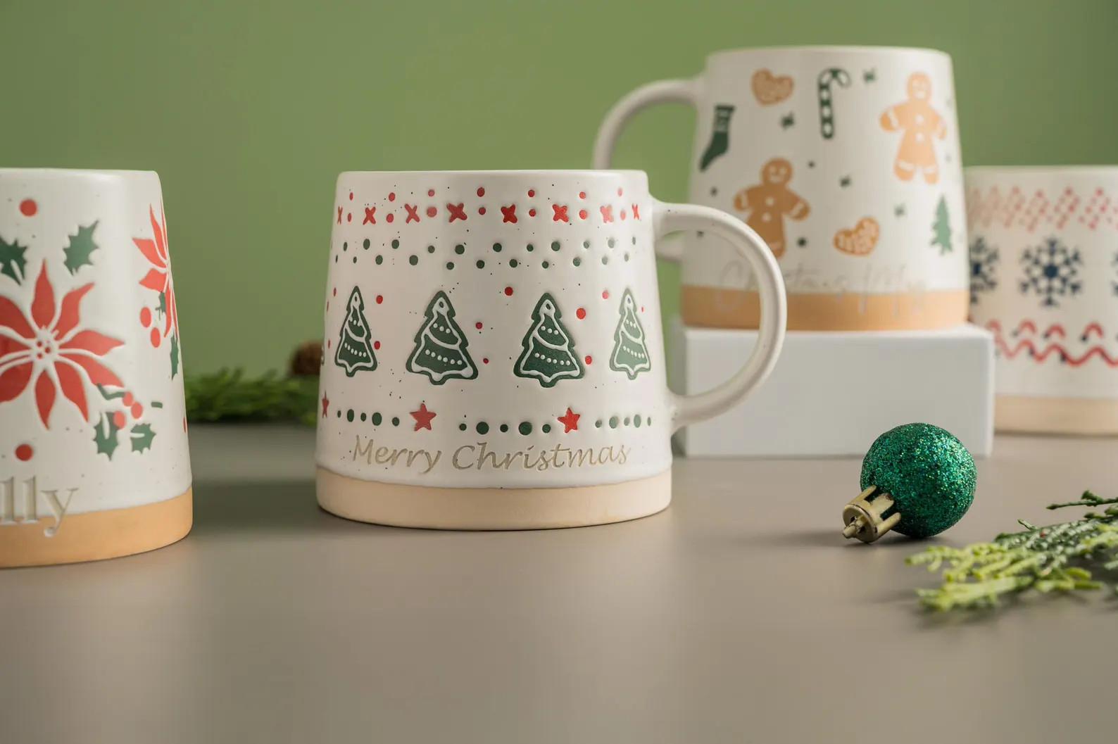 Ceramic Merry Christmas mugs with Christmas tree, poinsettia and gingerbread designs displayed together, delightful neighbor Christmas gift ideas for coffee lovers.