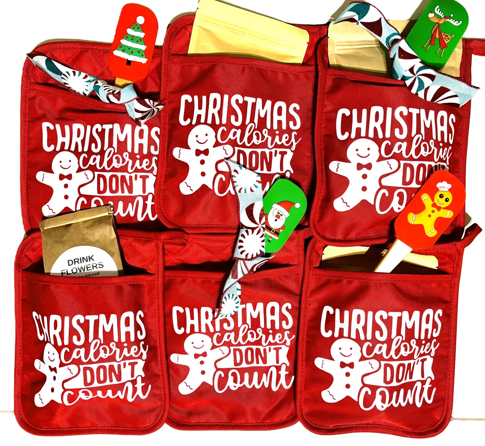 Red oven mitts printed with Christmas Calories Don't Count and gingerbread man, stuffed with festive spatulas, fun neighbor Christmas gift ideas.