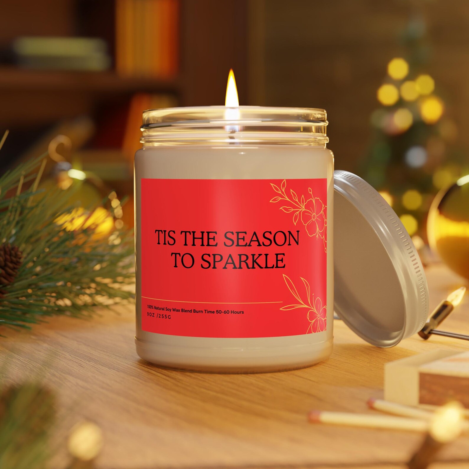 Lit soy wax candle with red Tis the Season to Sparkle label surrounded by pine and ornaments, ideal neighbor Christmas gift ideas.
