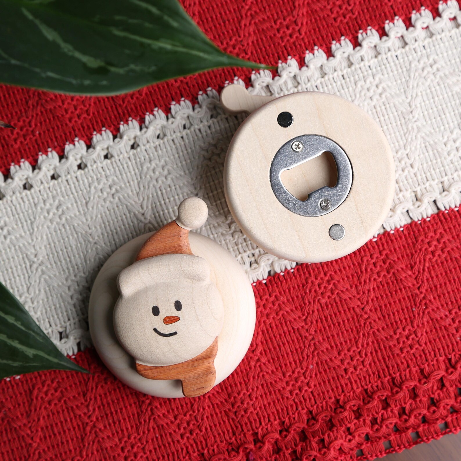 Wooden snowman fridge magnet bottle opener showing front and back on red knit fabric, cute and practical neighbor Christmas gift ideas.