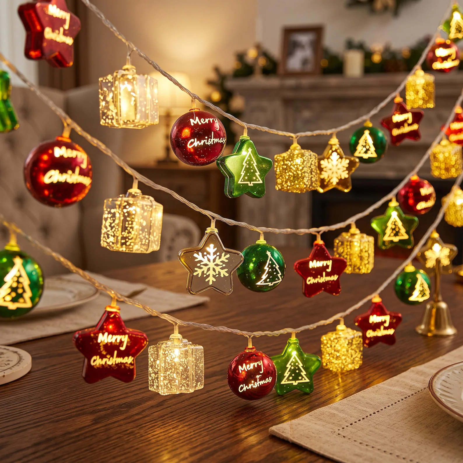 Three strands of festive LED string lights featuring glowing Merry Christmas balls, gift boxes, stars and tree shaped charms in red, green and gold, dazzling Christmas hostess gift ideas that instantly transform any room.