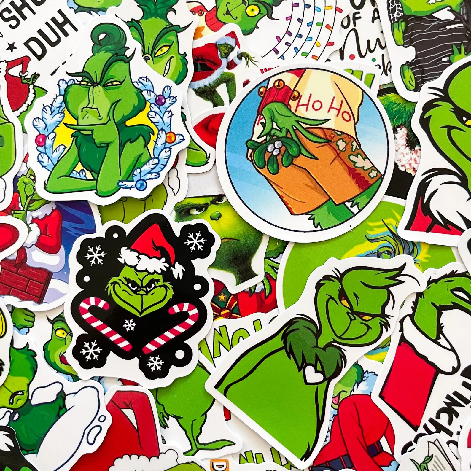 Colorful jumbo pile of assorted Grinch Christmas stickers in various fun poses and styles, a budget friendly and crowd pleasing Grinch party favor idea for kids and adults.