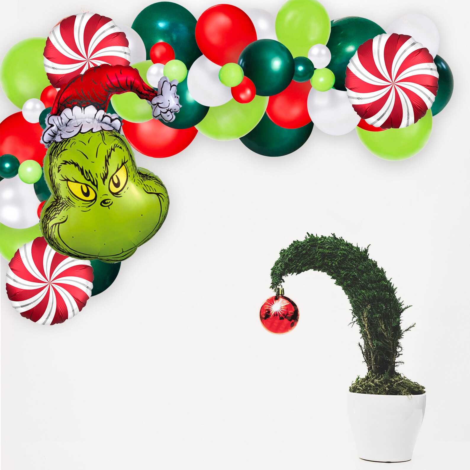 Grinch face foil balloon arch kit in red, green and white with peppermint swirl balloons beside a droopy Grinch tree, show stopping Grinch party decoration for the holidays.
