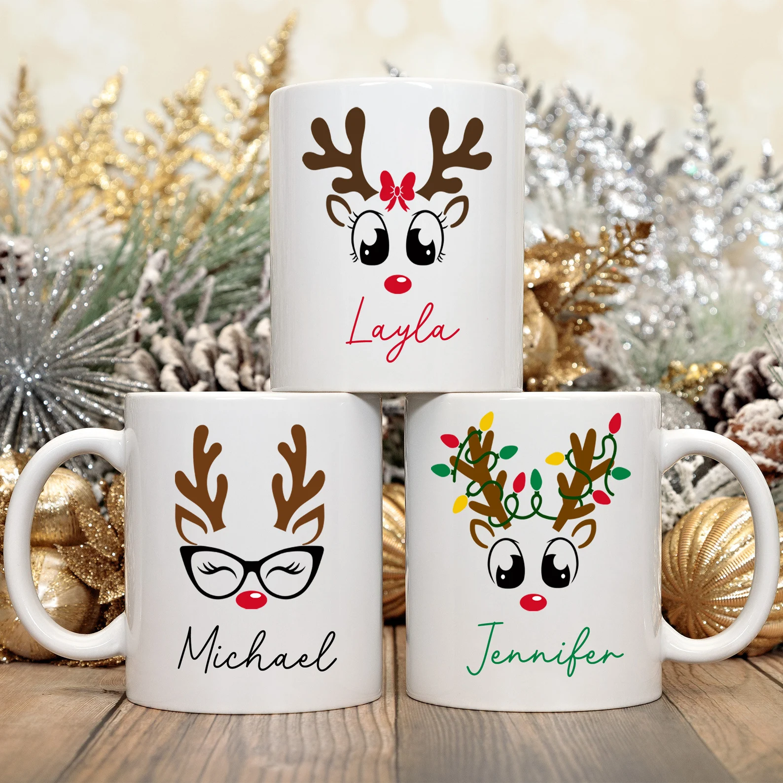 Three personalized white mugs featuring cute reindeer faces with bow, glasses and Christmas lights designs with individual names, adorable and giftable Christmas hostess gift ideas for coffee loving friends and family.