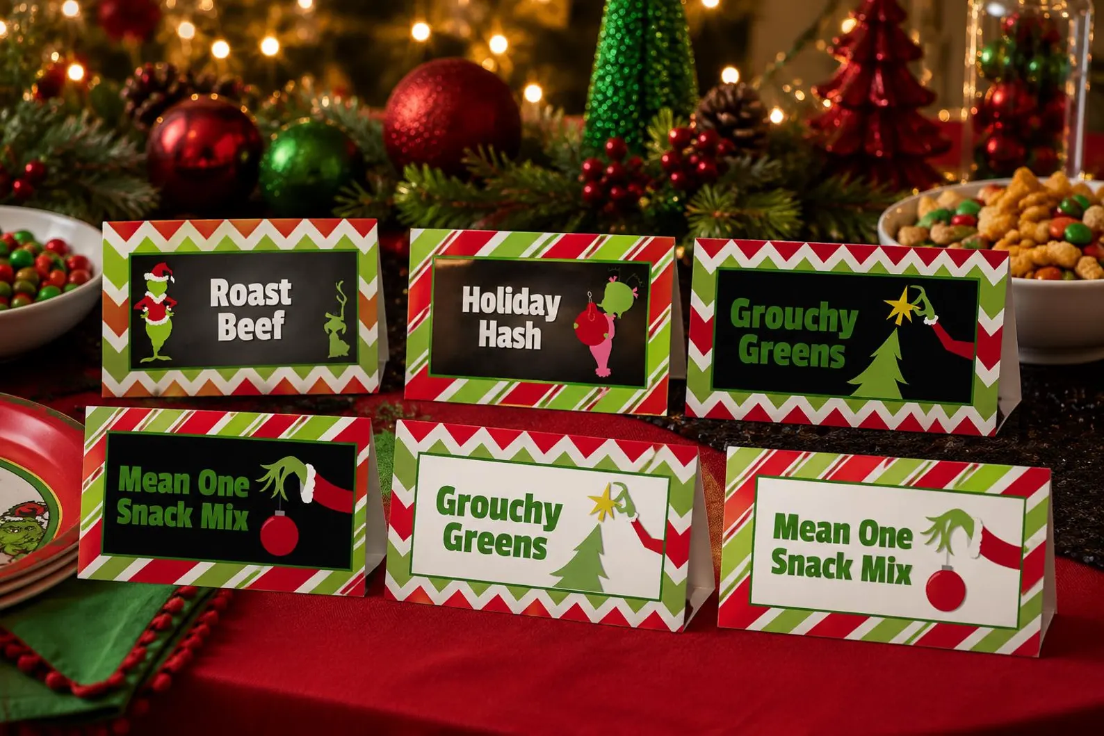 Six red and green chevron Grinch themed food tent cards labeled Roast Beef, Holiday Hash and Mean One Snack Mix on a festive party buffet table, creative Grinch party food labeling ideas.