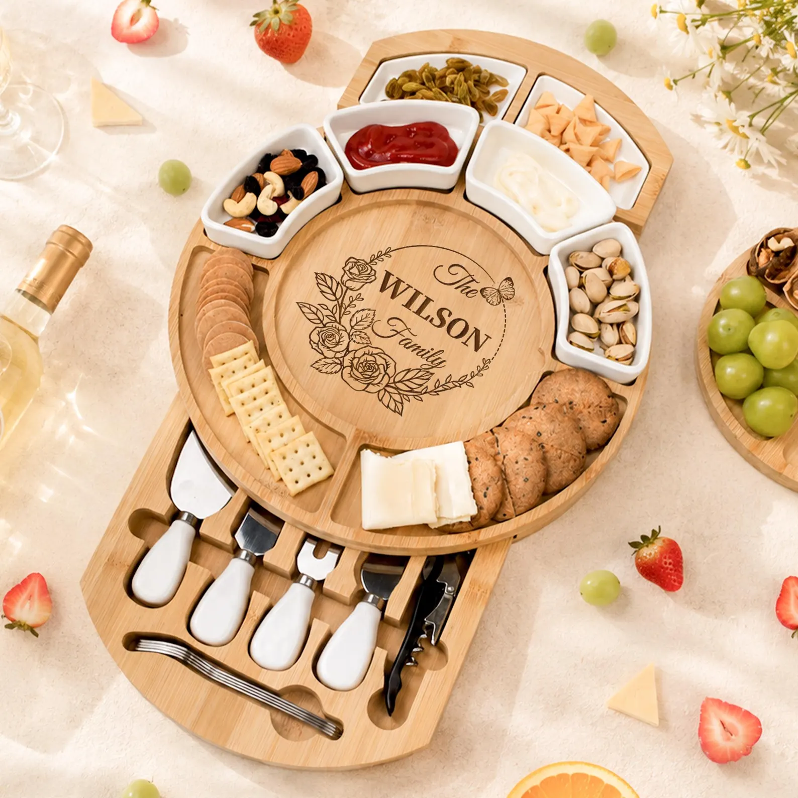 Personalized engraved bamboo charcuterie board with hidden knife drawer, ceramic dip bowls and rose floral design loaded with crackers, cheese, nuts and dips, a stunning and generous Christmas hostess gift ideas she will use all year.