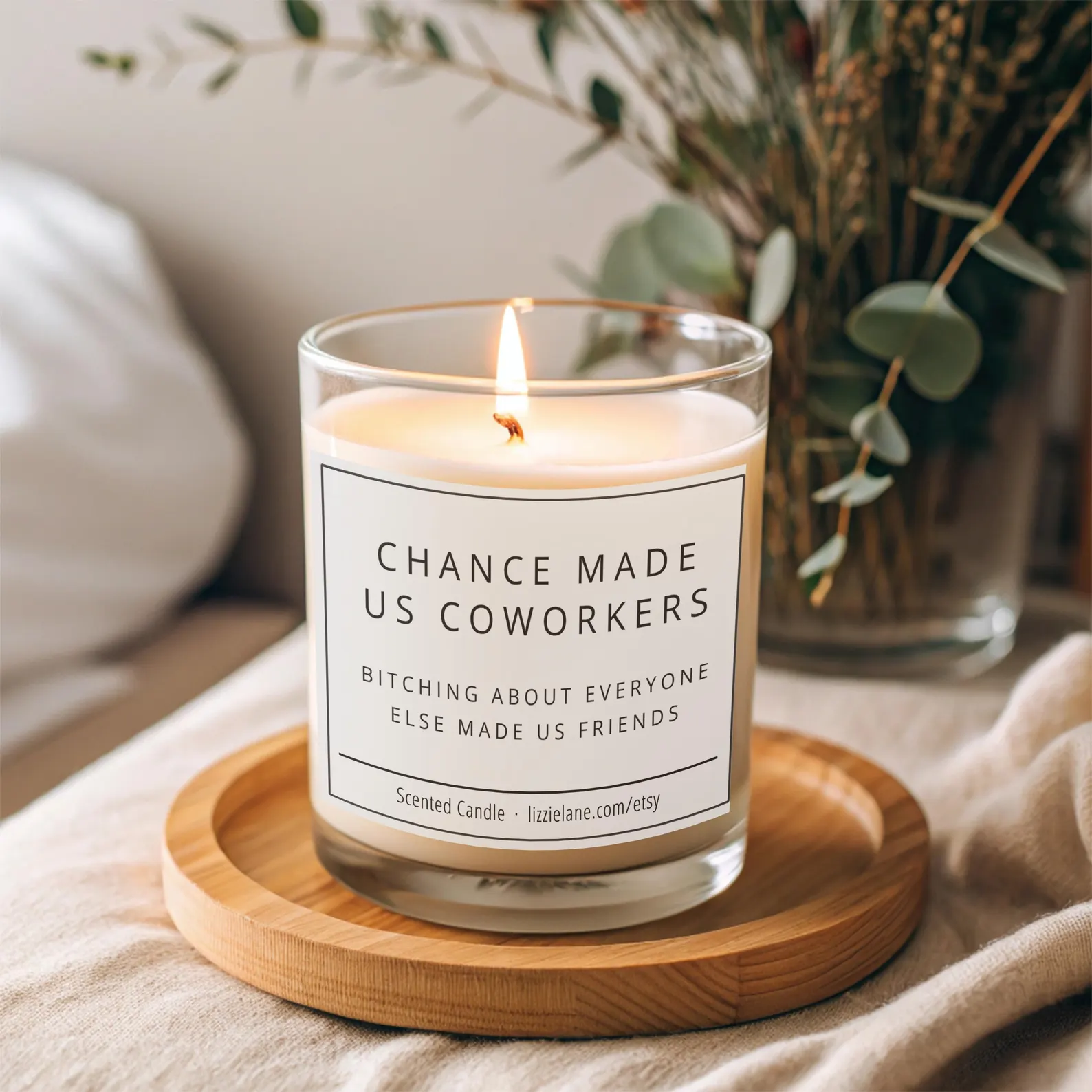 Lit scented candle with funny Chance Made Us Coworkers label on a wooden tray, one of the most hilarious Christmas gift ideas for coworkers.